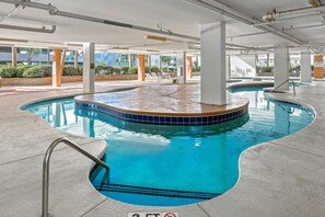 An indoor swimming pool with clear blue water, surrounded by a tiled deck and supported by white pillars. - 3-bedroom, 3-bathroom, 6th floor condo in Crescent Beach | Malibu Pointe - 604 (North Myrtle Beach)