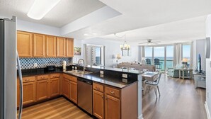 Una cocina moderna con armarios de madera, encimera negra y lavavajillas empotrado.