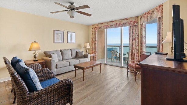 A living room with a sofa, two armchairs, a coffee table, a TV, and a ceiling fan. - Perfect 3 bedroom condo, just across from the beach! | Malibu Pointe - 1105 (North Myrtle Beach)