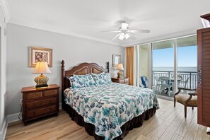 A bedroom with a large bed, wooden nightstands, a ceiling fan, and a balcony with outdoor seating. - Oceanfront and just a short walk from shops, restaurants, and bars! | Mar Vista Grande - 706 (North Myrtle Beach)