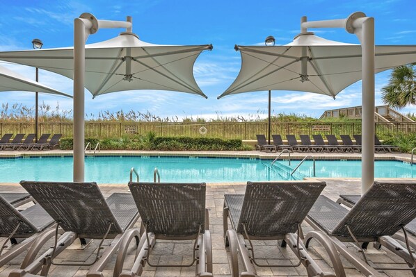 A poolside area with lounge chairs and umbrellas, a clear blue sky, and a sign indicating no diving allowed. - Oceanfront and just a short walk from shops, restaurants, and bars! | Mar Vista Grande - 706 (North Myrtle Beach)