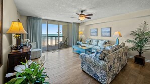 A spacious living room with a large sofa, a coffee table, and a view of the beach through a sliding glass door. - Oceanfront 3-bedroom, 3-bathroom condo, jetted tub, private balcony | Ocean Bay Club - 308 (North Myrtle Beach)