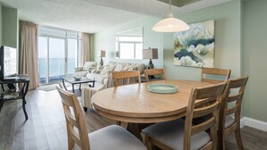 A dining area with a round wooden table, six chairs, and a hanging light fixture.