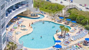 A large, multi-level swimming pool with various seating areas and a deck surrounding it.