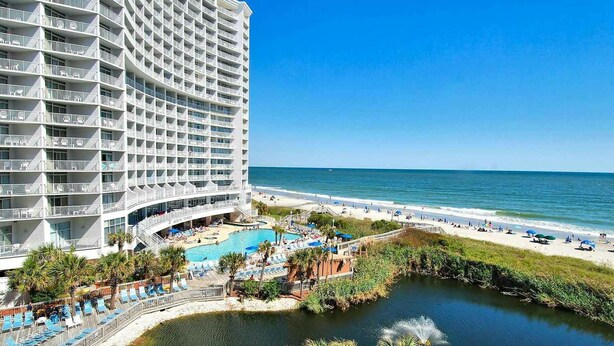 Een hotel met zwembad, strand en uitzicht op de oceaan.