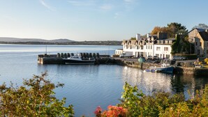A waterfront property with a dock, a large white building, and a view of the water. - Roundstone Quay (Roundstone)