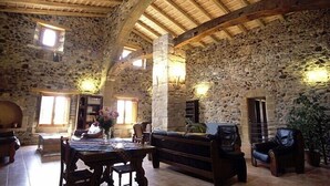 Un interior rústico de piedra con vigas de madera, una chimenea de piedra y una zona de estar acogedora.