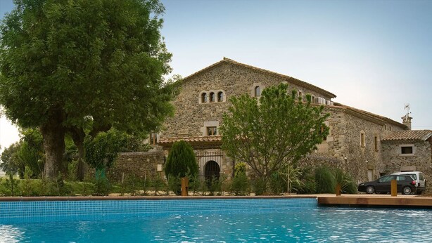 Un edificio de piedra con piscina delantera.