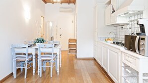 Una cocina moderna con armarios blancos, techo de madera y un comedor con mesa y sillas.