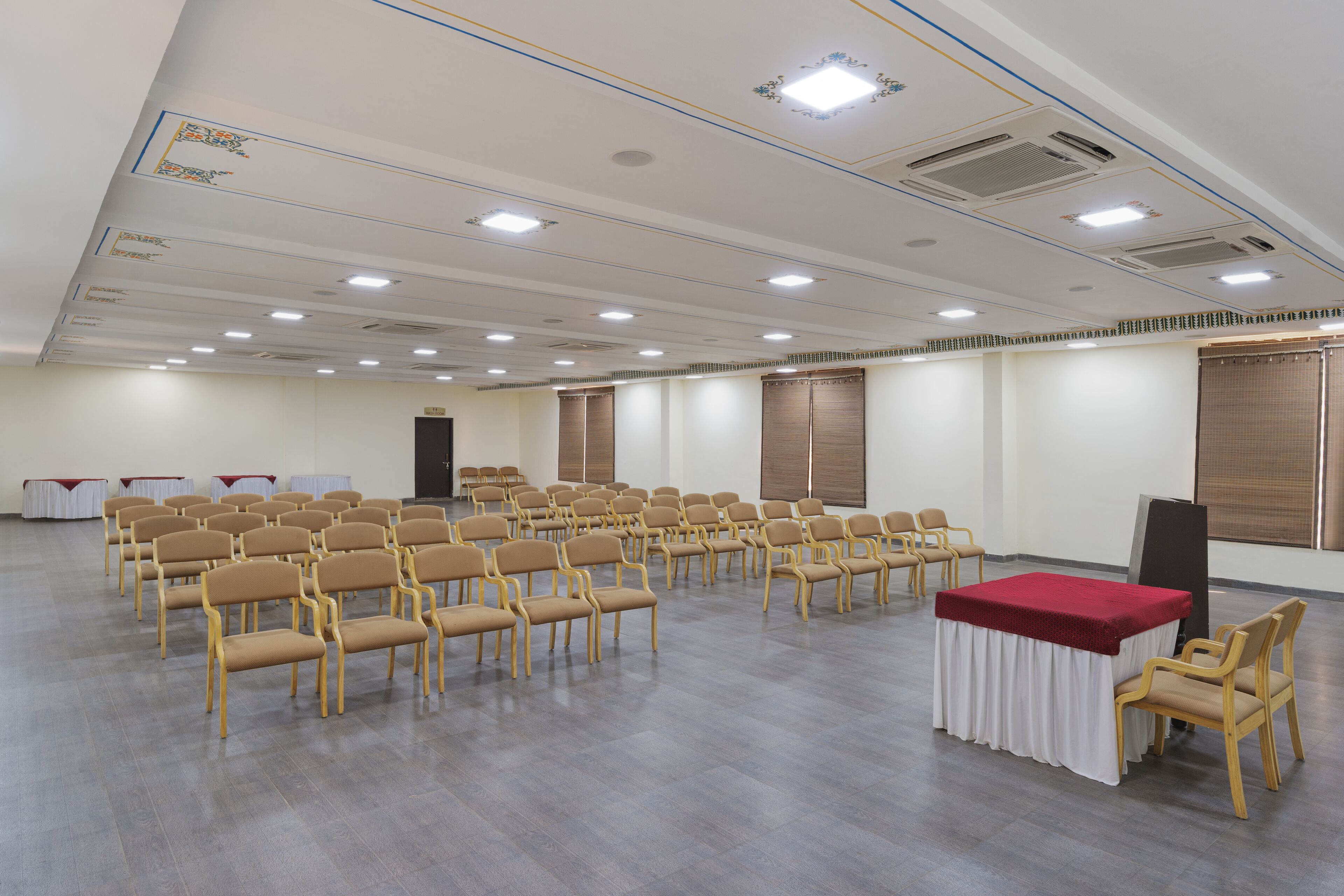 A conference room with rows of chairs, a table with a red tablecloth, and a projector screen.