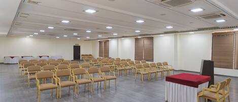 A conference room with rows of chairs, a table with a red tablecloth, and a projector screen.