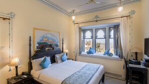 A well-appointed bedroom with a large bed, a desk, and a window with curtains. - The Kumbha Bagh (Kumbhalgarh)
