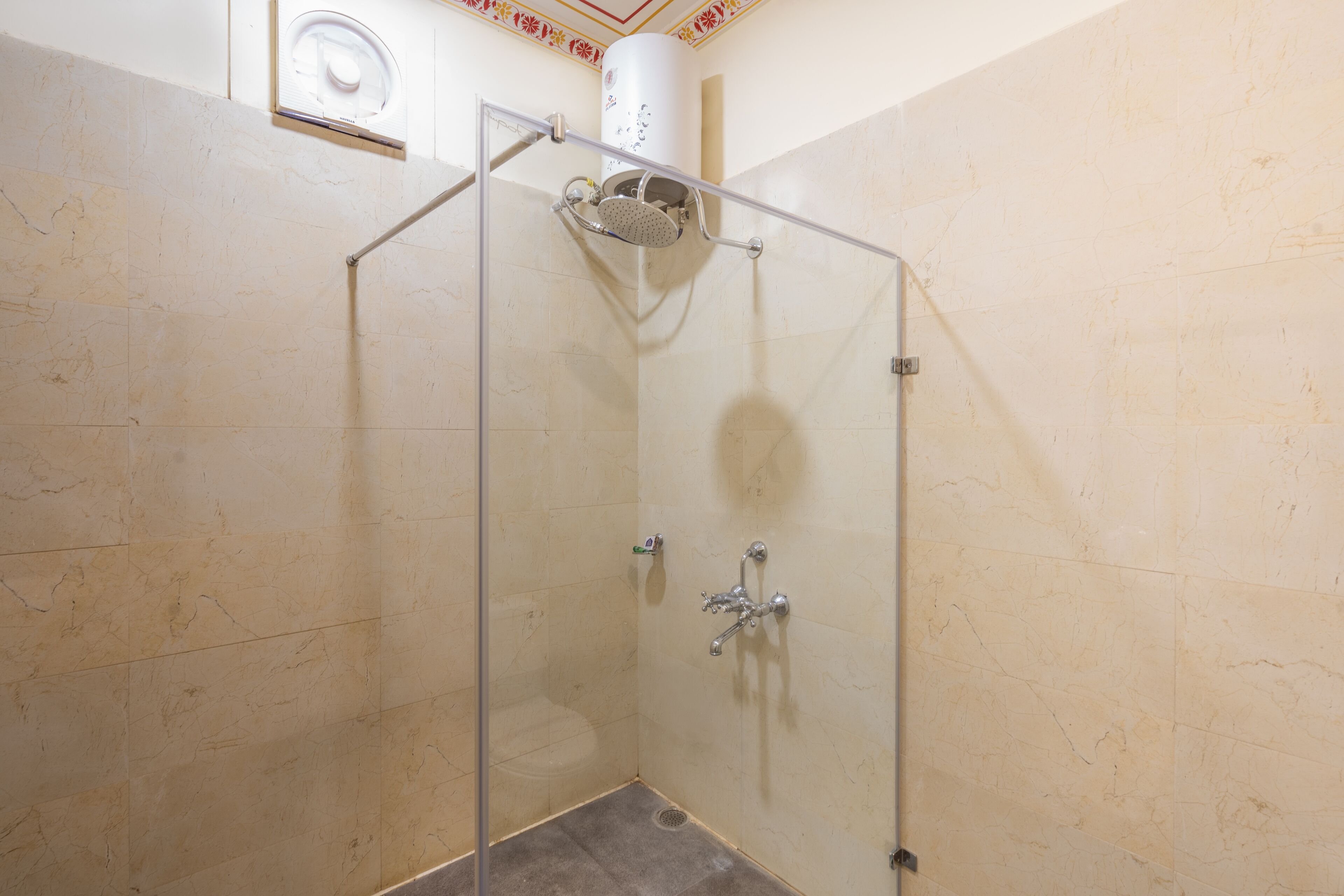 A glass-enclosed shower with a handheld showerhead and a wall-mounted faucet.