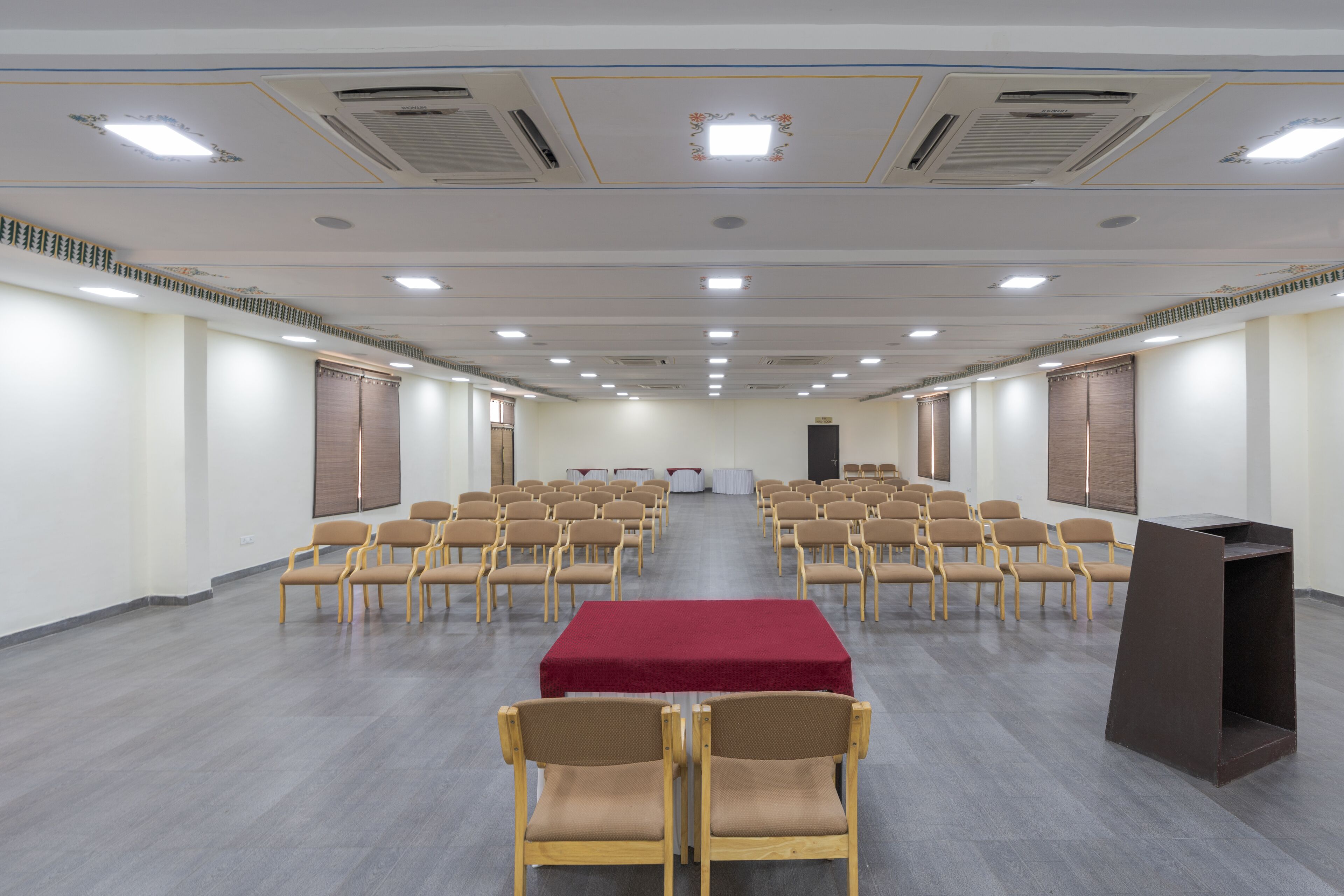 Un salón de conferencias con filas de sillas, una mesa central y un atril.