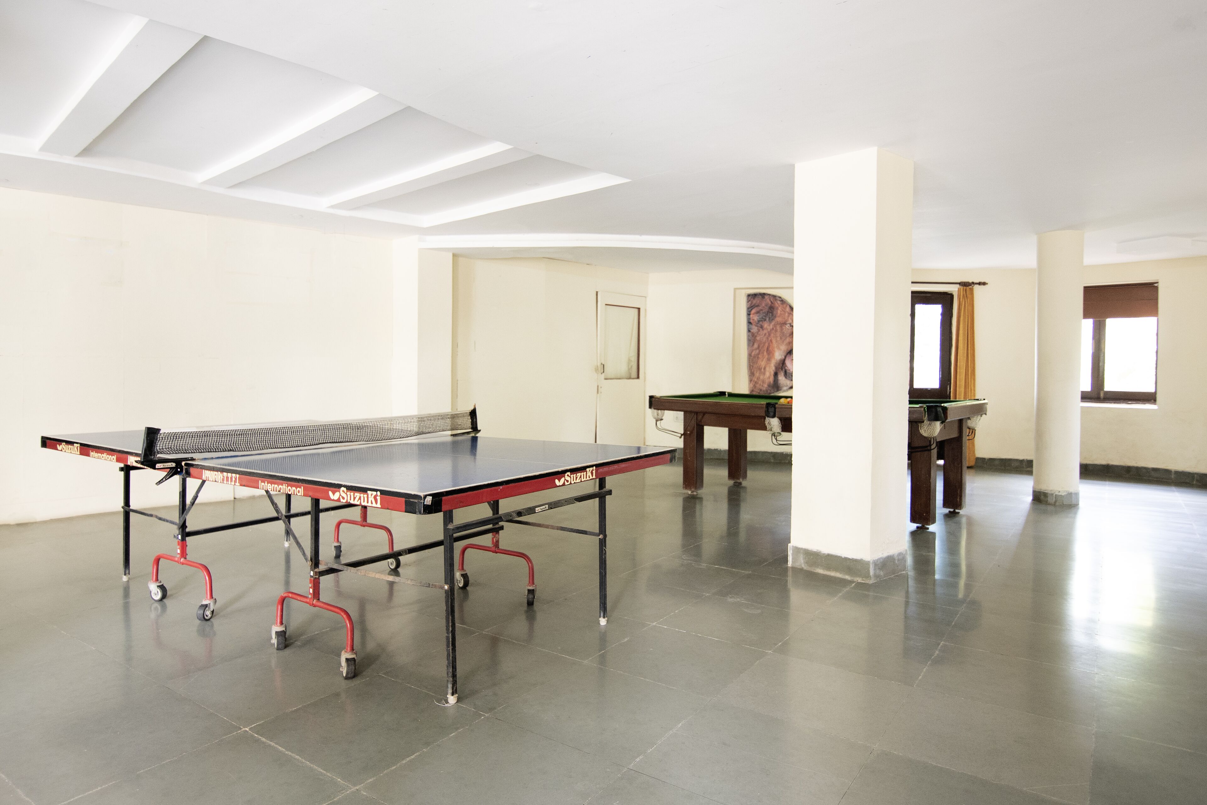 A spacious room with a ping pong table, a pool table, and a billiards table.