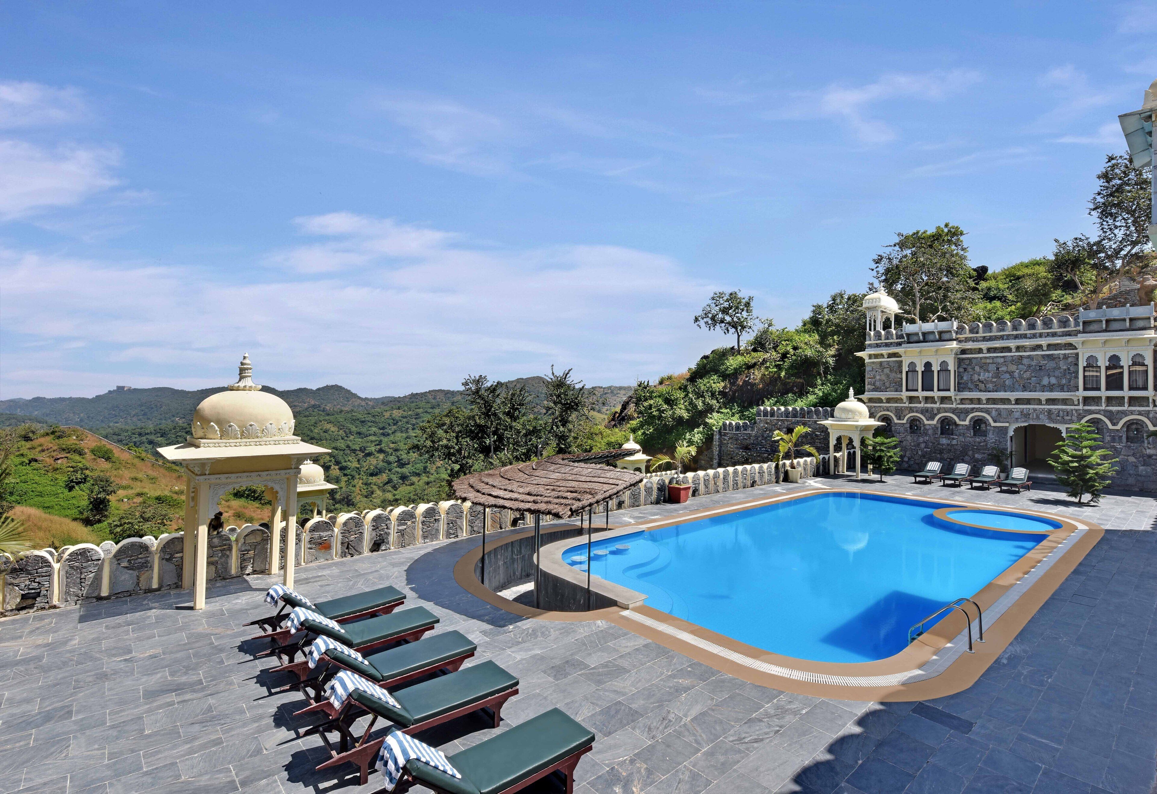 A rooftop swimming pool with lounge chairs and a view of the surrounding landscape.