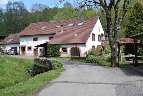 Un chalet traditionnel doté d’un toit en pente, d’un porche en bois et d’une petite construction en bois attenante.