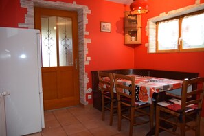 Une cuisine de taille réduite, équipée d’un réfrigérateur, d’une porte en bois et d’une table à manger avec des chaises.