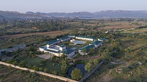 Vista aérea de un extenso complejo hotelero moderno con múltiples edificios, techos verdes y céspedes bien cuidados.