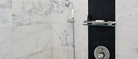 A modern shower with a handheld showerhead and a wall-mounted faucet.