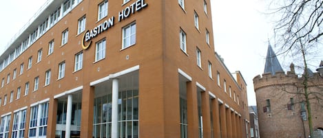 A modern hotel building with a prominent sign reading "Bastion Hotel."