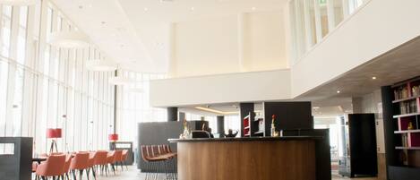 A spacious lobby with a central reception desk, seating area, and a large windowed wall.