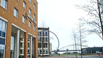 A hotel with a modern facade, large windows, and a prominent circular structure in front.