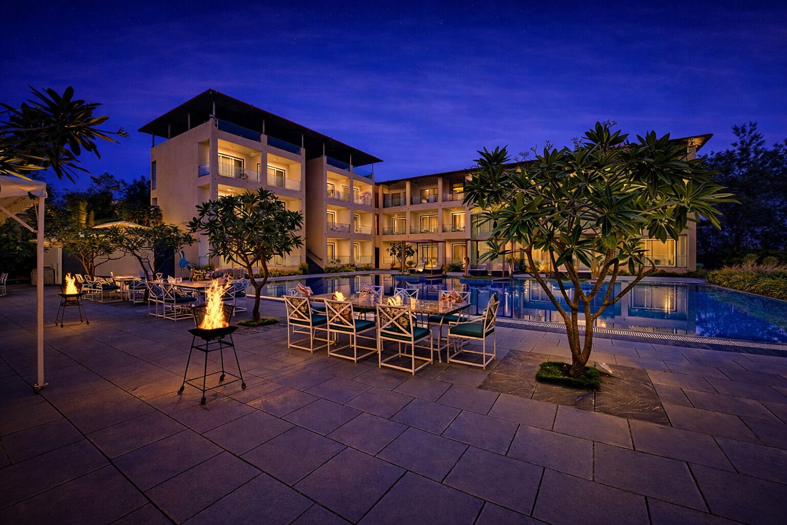A hotel with a pool, outdoor seating, and a fire feature.