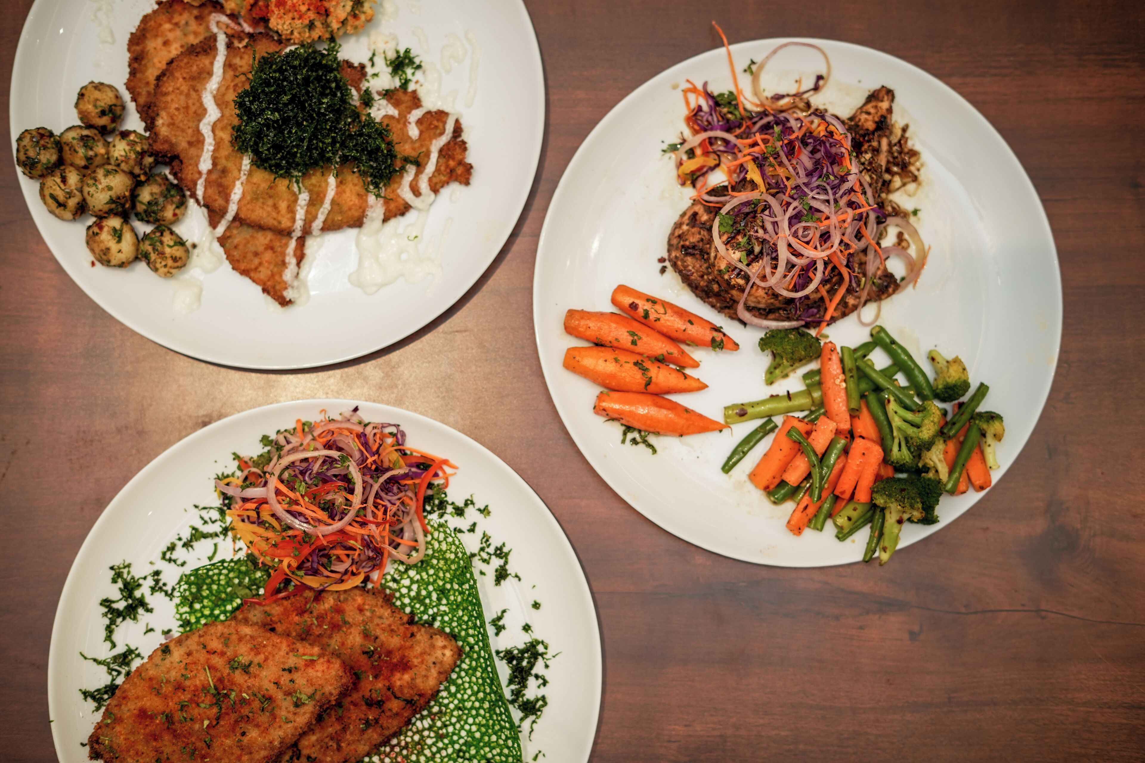 Three plates of food with various vegetables and meat.
