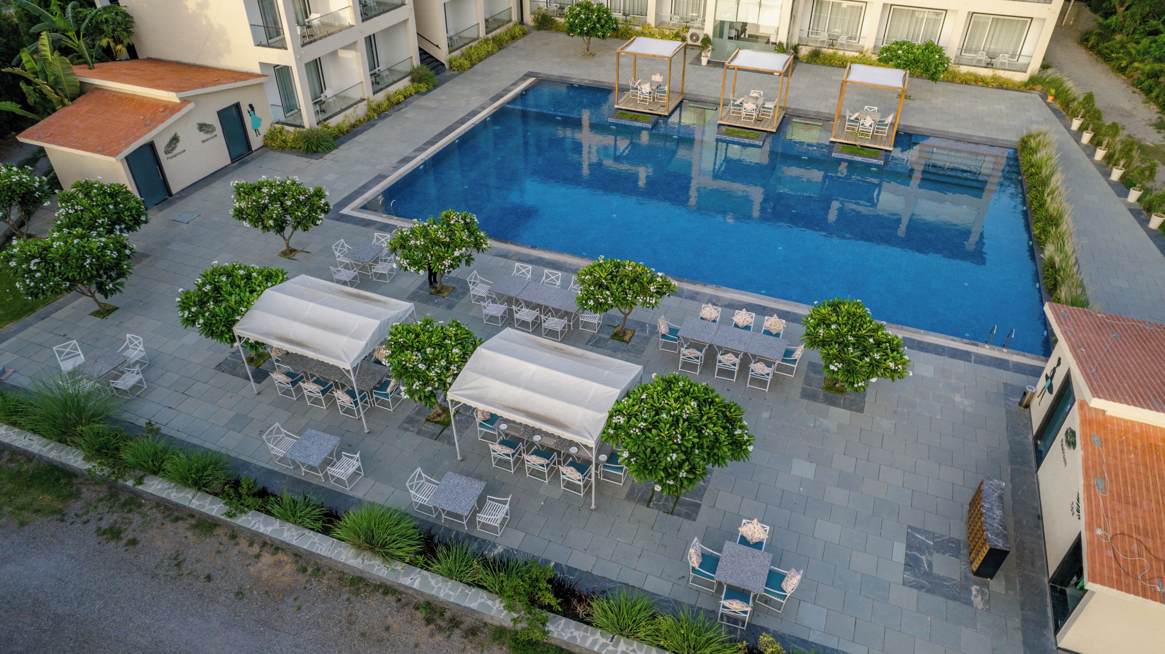 A swimming pool with lounge areas, surrounded by potted plants and outdoor furniture.