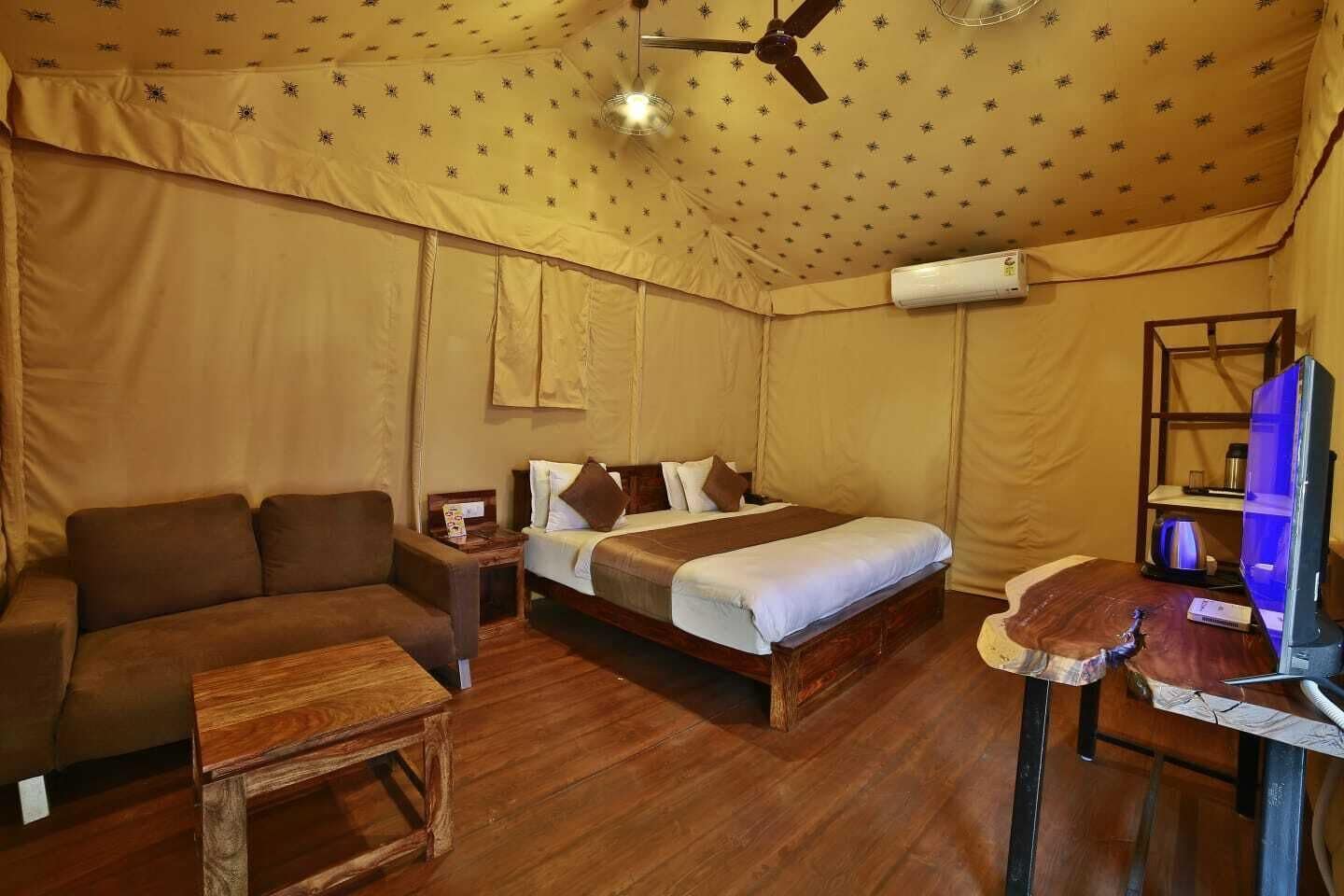 A tent-style room with a bed, a sofa, a small table, and a TV.