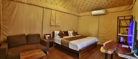 A tent-style room with a bed, a sofa, a small table, and a TV.