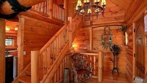 Interior de madera con una escalera, una araña y decoración rústica.
