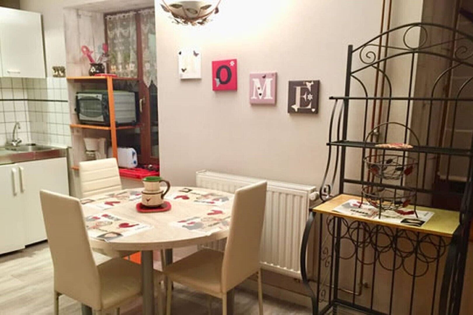 A dining area with a round table, chairs, a radiator, and a metal rack with items on it.