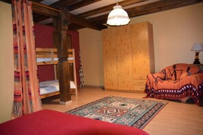 A room with a bunk bed, a wardrobe, a patterned rug, and a hanging light fixture.
