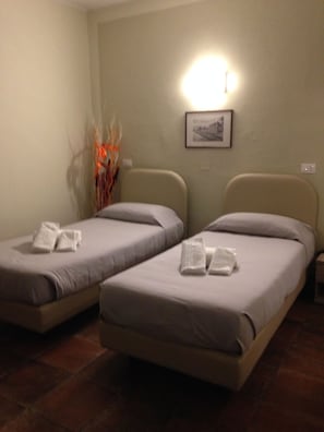 Two single beds with pillows and towels, a wall-mounted light, and a framed picture on the wall. - Albergo San Michele Ristorante Torino (Mortara)