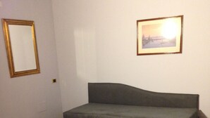 Une pièce avec un canapé gris, un plancher en bois et deux tableaux encadrés accrochés aux murs.