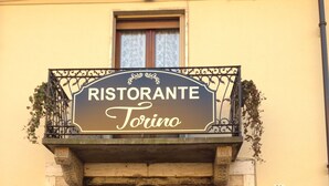 Un bâtiment sur lequel on peut lire les inscriptions « Ristorante Torino » et « Albergo San Michele », ce qui indique qu’il s’agit à la fois d’un restaurant et d’un hôtel.