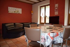 Ein gemütliches Wohnzimmer mit einer Couch, einem runden Esstisch und einem Fernseher.