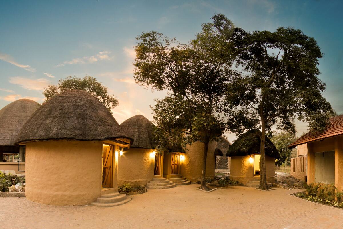 A series of thatched-roof structures with a paved walkway leading to a central entrance.