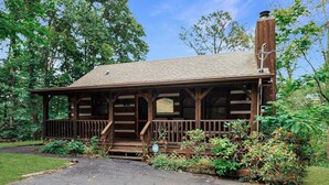 A rustic cabin with a wooden exterior, a porch, and a chimney. - Gettin' Lucky: Hit the Jackpot in the Smokies (Pigeon Forge)