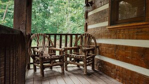 A wooden porch with two wicker chairs and a wooden table. - Gettin' Lucky: Hit the Jackpot in the Smokies (Pigeon Forge)