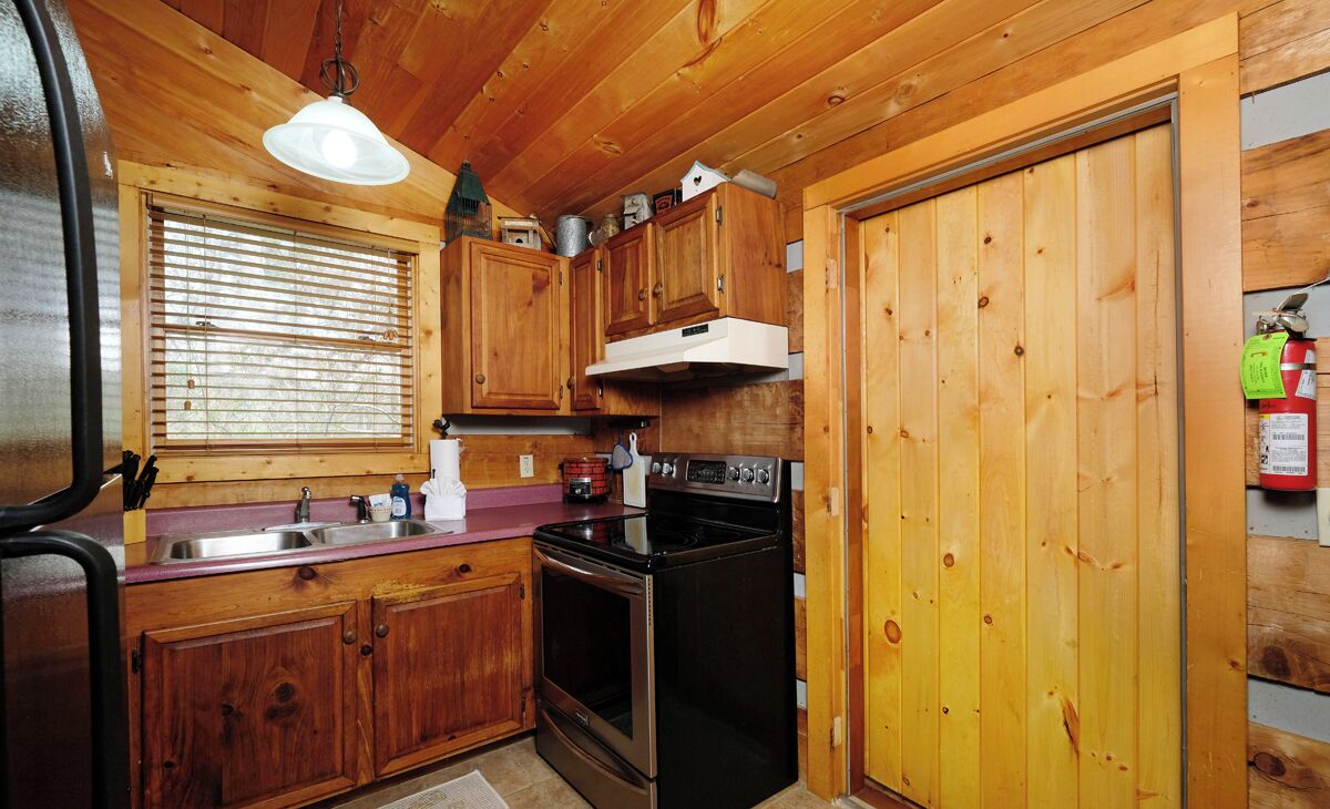 A compact kitchen with wooden cabinets, a stove, and a sink.