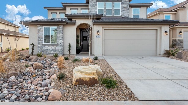 A two-story house with a stone facade, a garage, and a landscaped front yard with rocks and plants. - Desert Living 5 Bedroom Home by RedAwning (Washington)