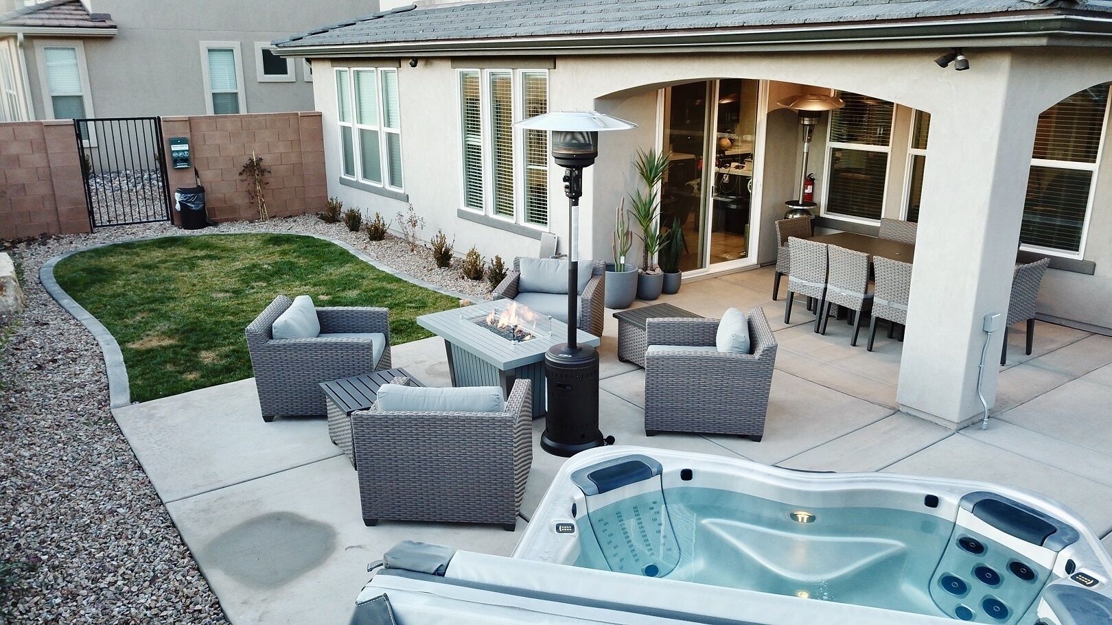 A backyard with outdoor furniture, a hot tub, and a patio area.