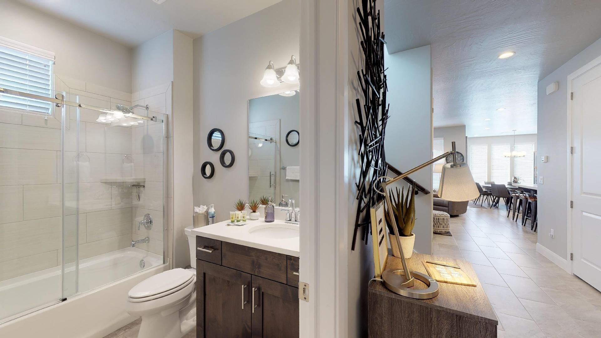 A modern bathroom with a glass shower enclosure, a white toilet, and a vanity with a mirror and sink.