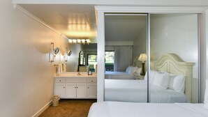 Une chambre d’hôtel avec un grand lit, une coiffeuse avec un miroir et une porte coulissante donnant sur un balcon.