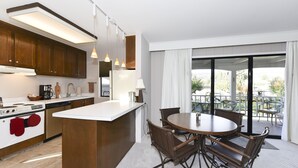 Una cocina moderna con una isla central, zona de comedor con sillas y vistas al exterior a través de grandes puertas correderas.