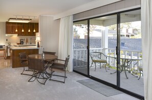 Une cuisine moderne dotée d’un éclairage suspendu, un coin repas avec une table ronde et des chaises, et un balcon avec un espace salon extérieur.
