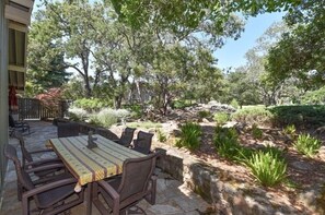 An outdoor patio with a table and chairs, surrounded by a garden with various plants and trees. - 824 Oak Creek At Silverado 3 Bedroom Condo by RedAwning (Napa)